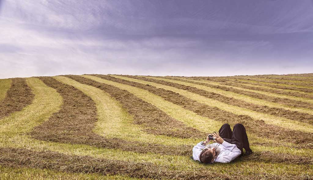 Man laying in a field using a phone