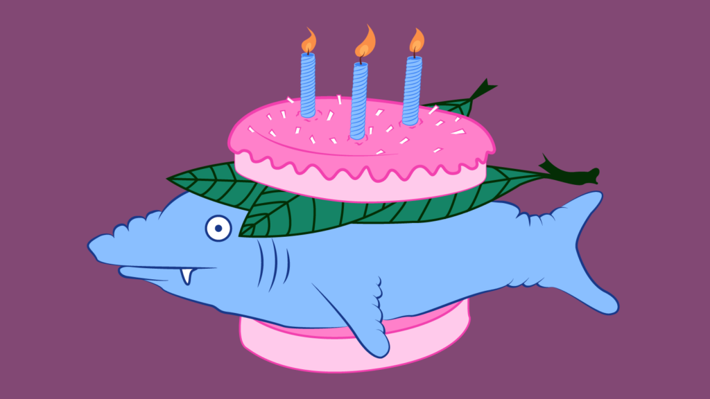 An illustration of a faux burger. The bun is a frosted cake cut in half with lit candles as the topping. The cake bun holds a shark-looking fish with a confused expression along with some seaweed-type leaves.