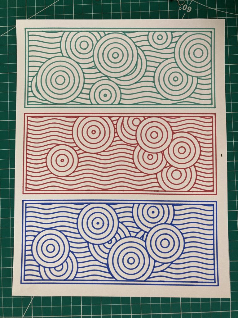 Three different framed geometric circle patterns: One in green, one in red, and one in blue. On white paper.
