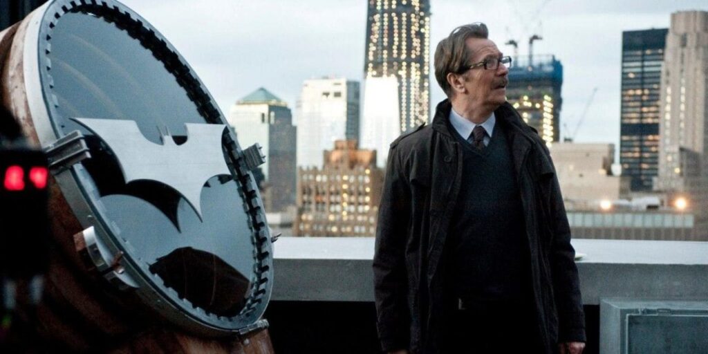A frame from Christopher Nolan's Batman movies of Commissioner Gordon standing on the rooftop preparing to light the batsignal.